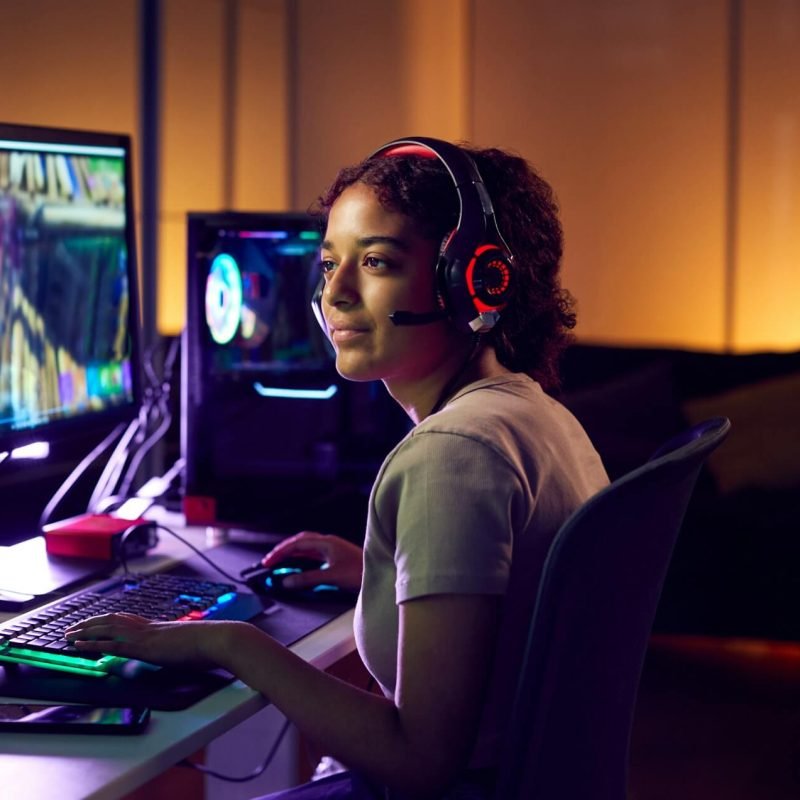 teenage-girl-wearing-headset-gaming-at-home-using-dual-computer-screens.jpg